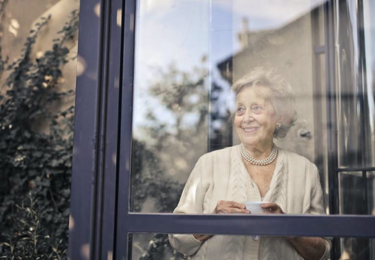 Starsza kobieta z filiżanką przy oknie